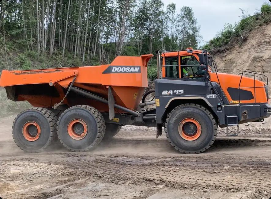 Большой оранжевый самосвал Doosan DA 45 30088 едет по грунтовой дороге