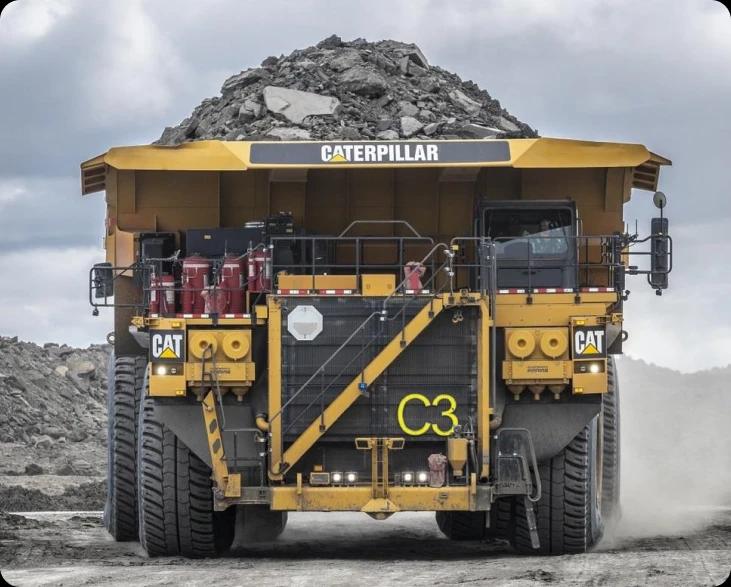 Большой самосвал Caterpillar 797F едет по грунтовой дороге